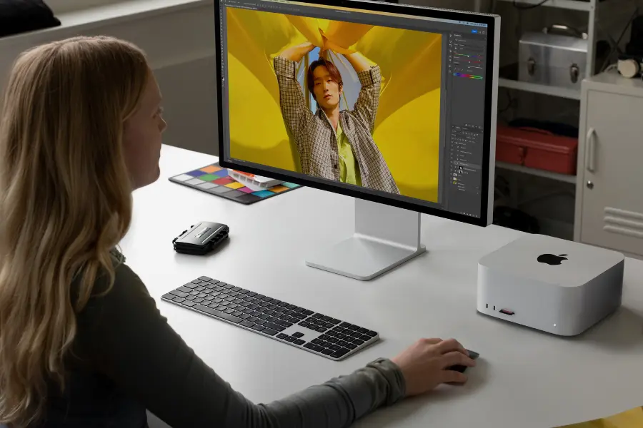 a woman sitting at a desk with a Mac Studio M2 Max